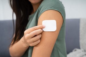 Woman applying hormone patch onto upper arm.
