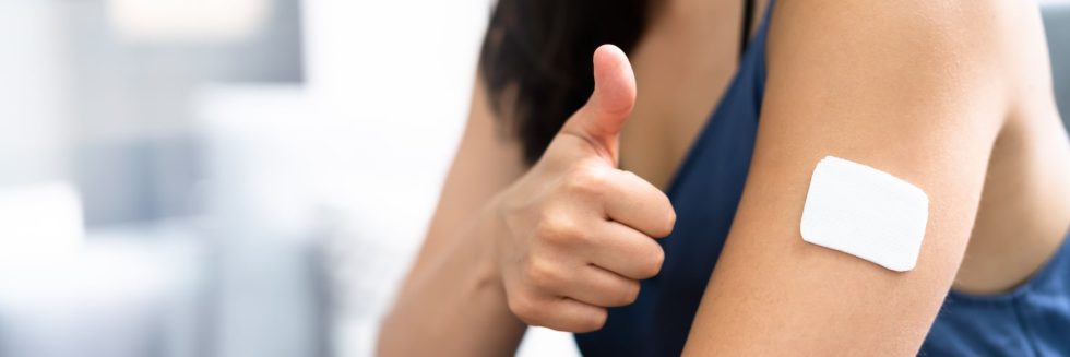 Woman giving a thumbs up with a bandage on her arm after getting the birth control implant
