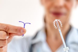 Woman holding two different types of IUD for birth control.