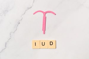 An IUD sitting on a granite countertop with the letters I-U-D